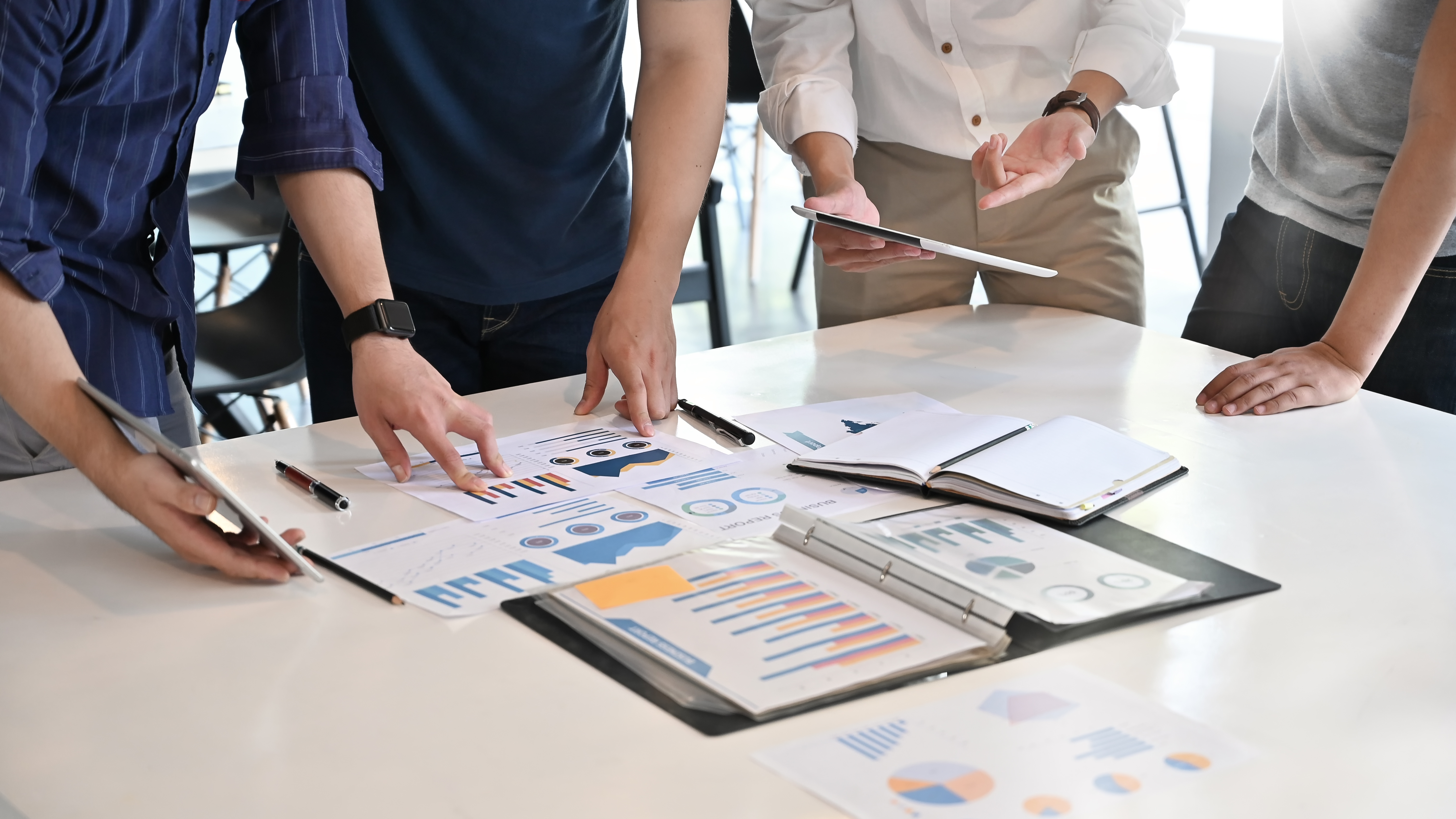 4 pessoas analisando dados em folhas em cima de uma mesa